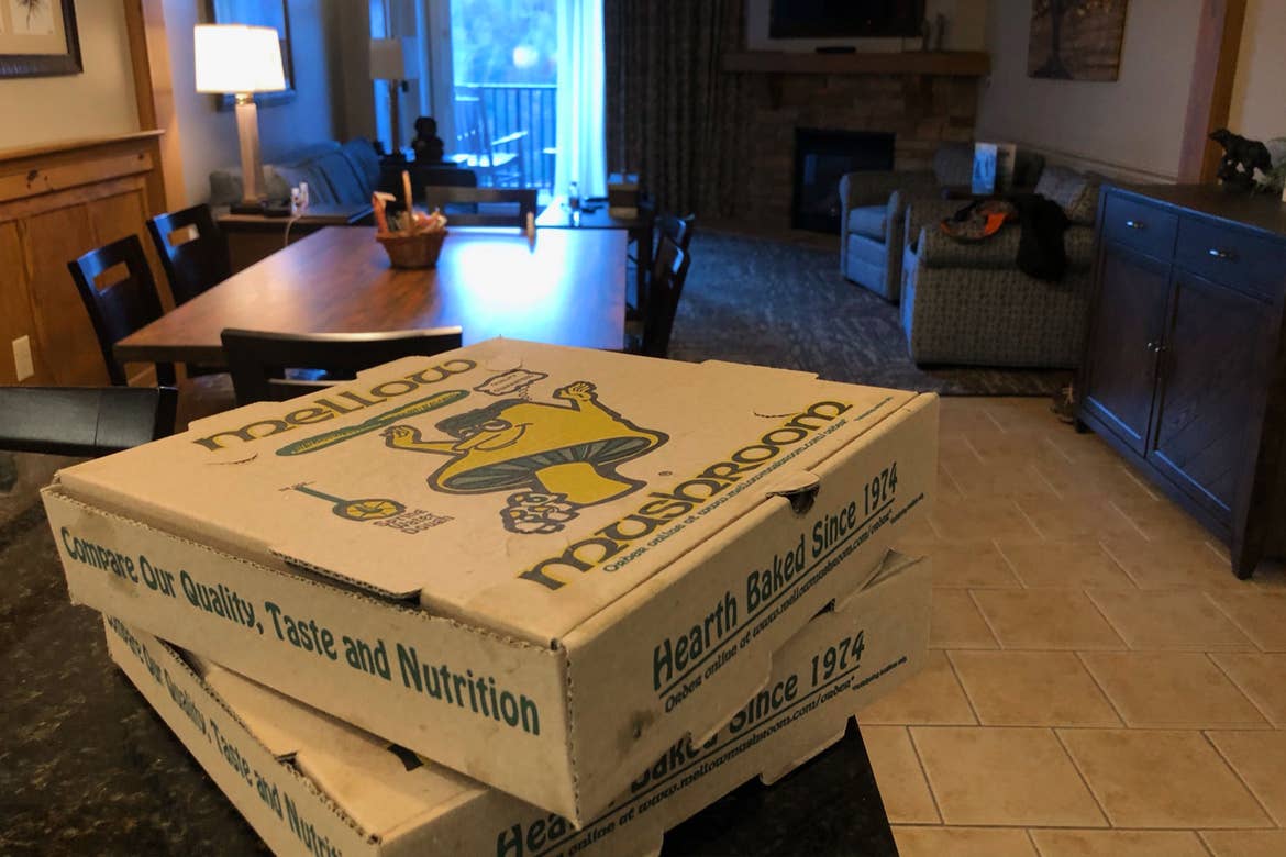 Two pizza boxes placed on a black countertop in a villa.