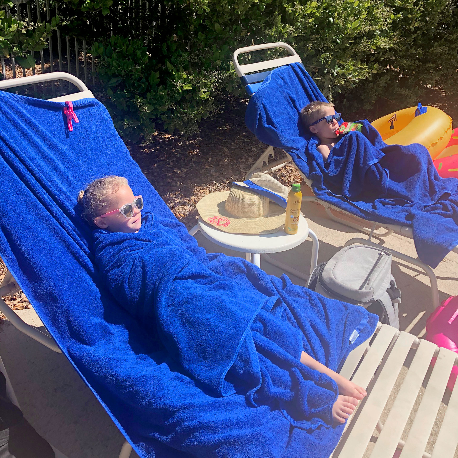 Featured Contributor, Brianna Steele's children sit wrapped in blue towels after a dip in the pool.