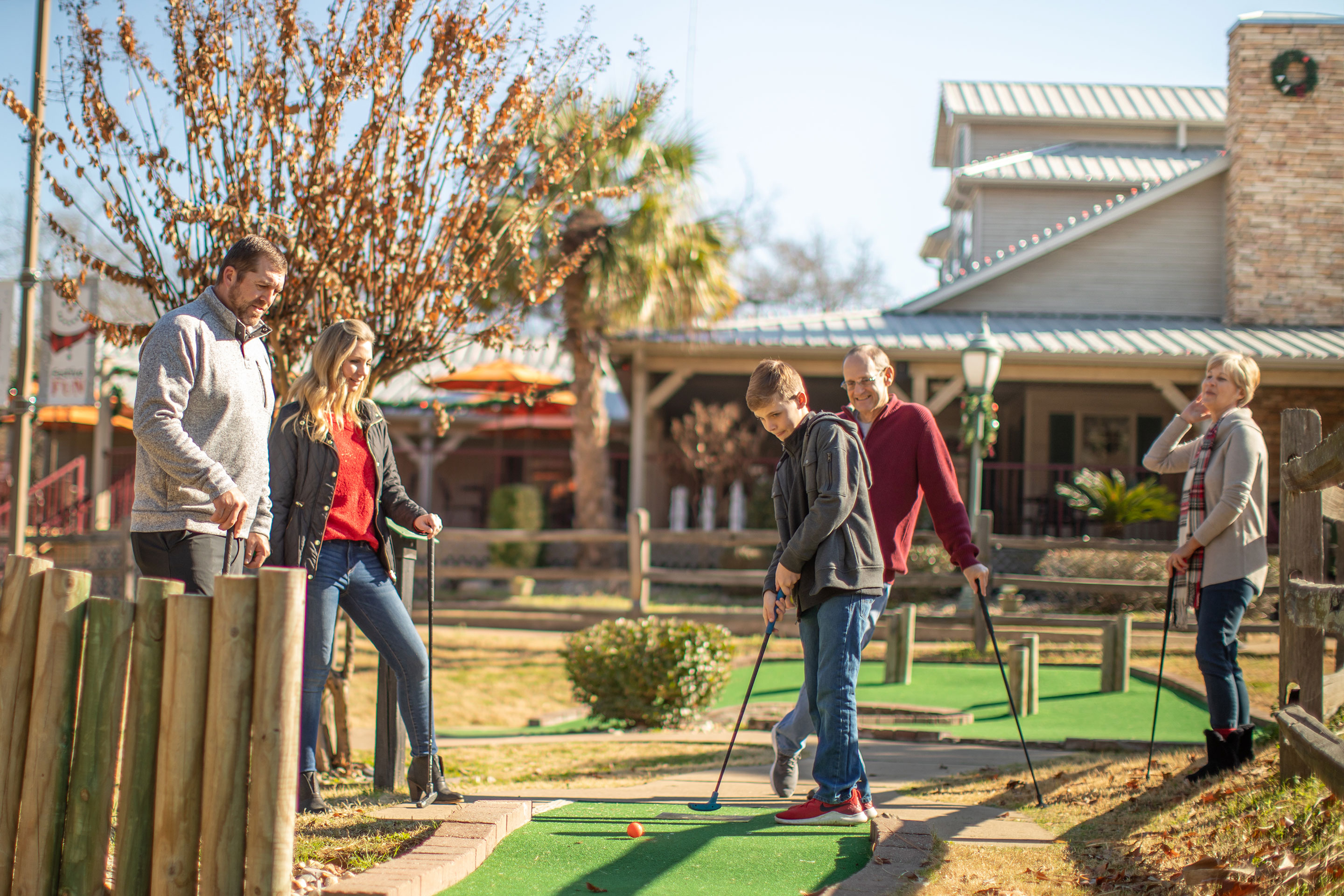 The Nall family gathers around the hole for a mini-golf game.