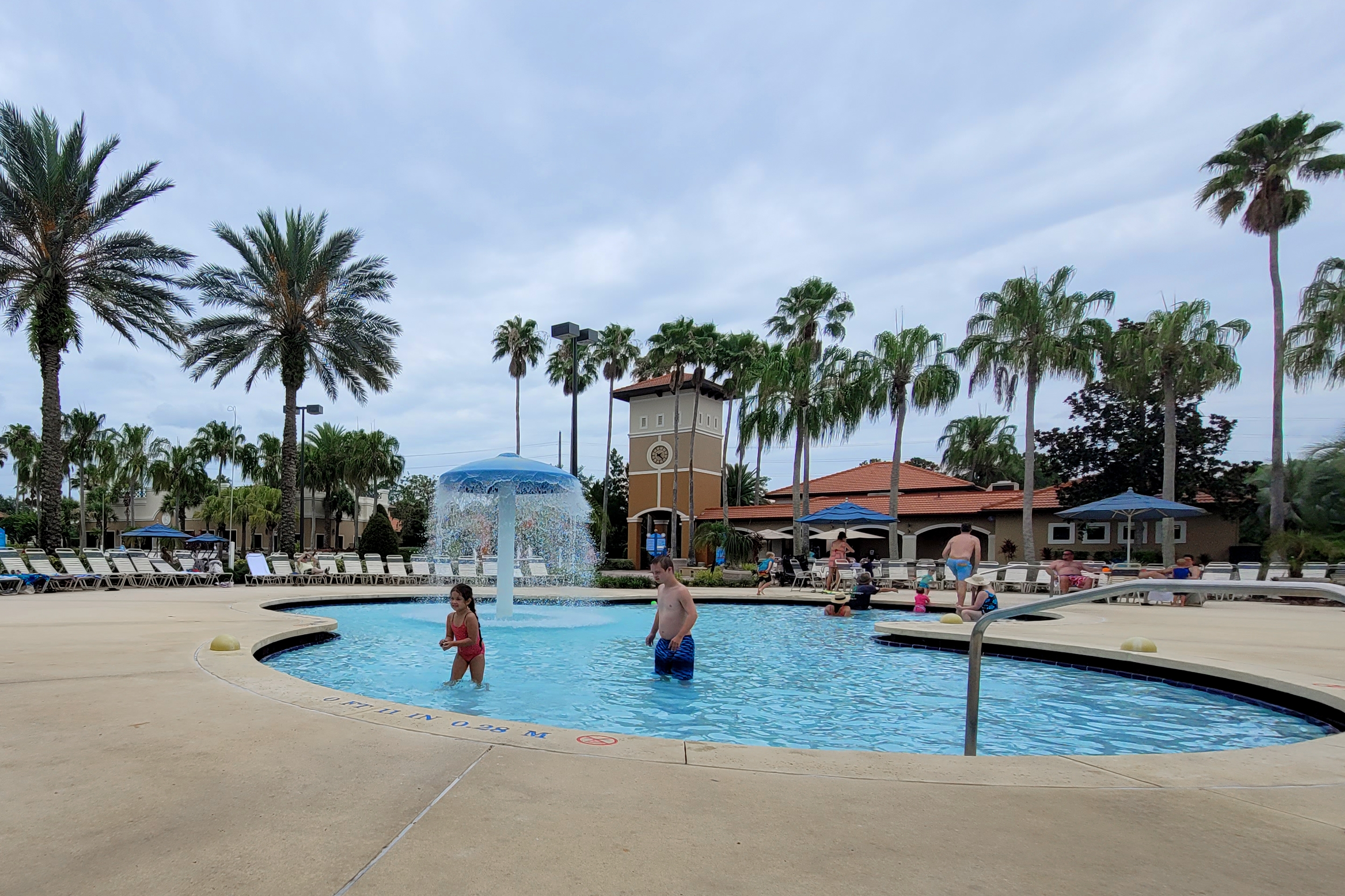 A young boy (right) and a young girl (left) play in an outdoor pool.