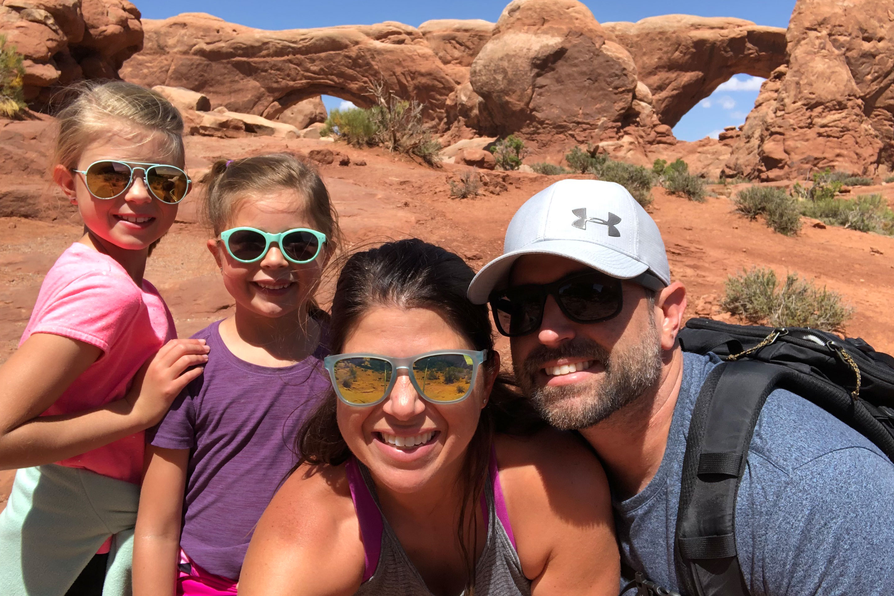 Author, Chris (middle), poses with her husband, Josh (right), and their two daughters Kyndall and Kyler (left) in front of the rock formations in Utah's Delicate Arch Window Arches.