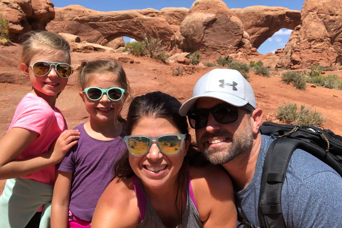 Author, Chris (middle), poses with her husband, Josh (right), and their two daughters Kyndall and Kyler (left) in front of the rock formations in Utah's Delicate Arch Window Arches.