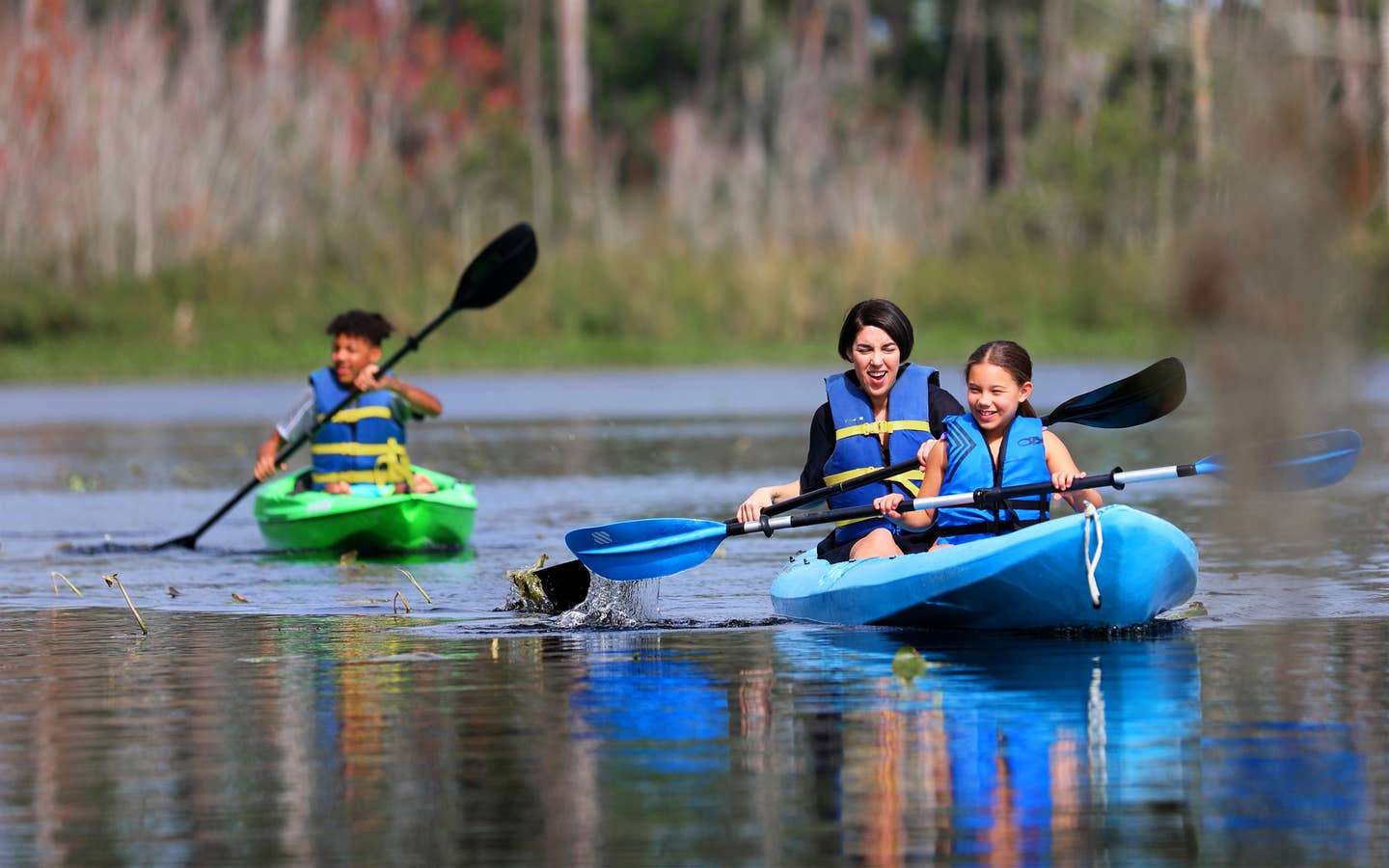 Featured Contributor, Clarissa Laskey (middle), kayaks with her daughter (right) in a blue kayak while her son (left) kayaks in his own green kayak.
