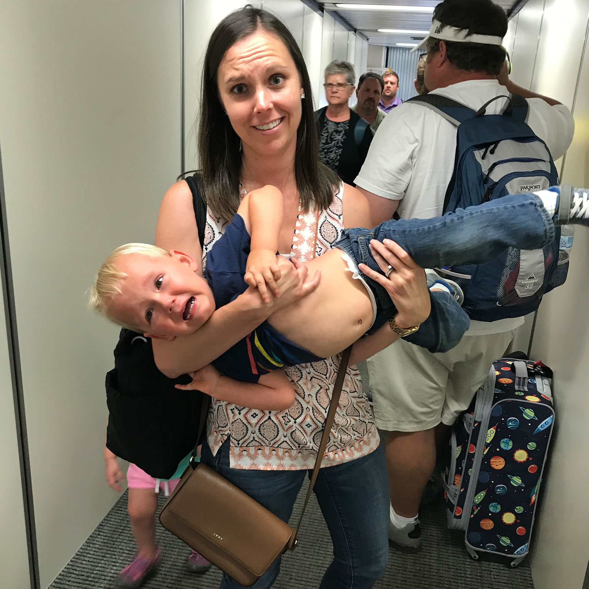 Author, Sarah Conroy, holds her son, Logan, in the boarding queue as he expresses much enthusiasm for their upcoming flight.