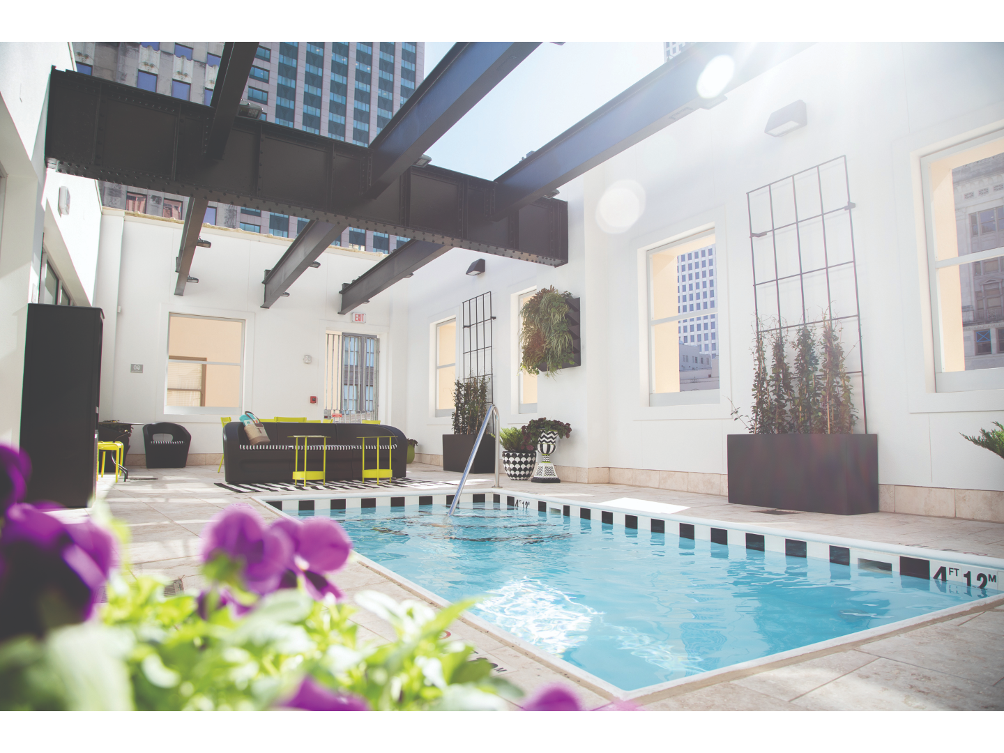 Boutique resort pool, with open ceiling and large buildings behind.