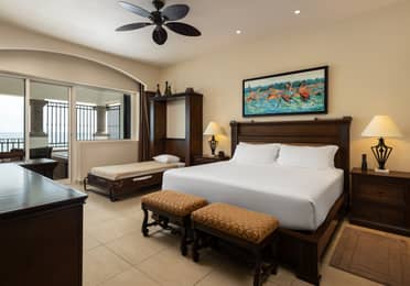 Beachfront suite bedroom with king bed, daybed, and ocean views.