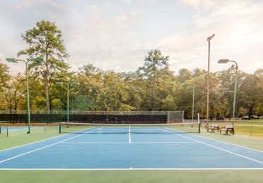 Outdoor tennis court surrounded by trees at Holly Lake Resort in Texas.