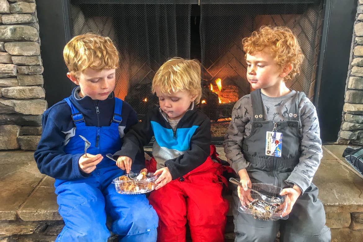 Jessica's three sons sit on the hearth with snowpants enjoying a delectable carrot cake.