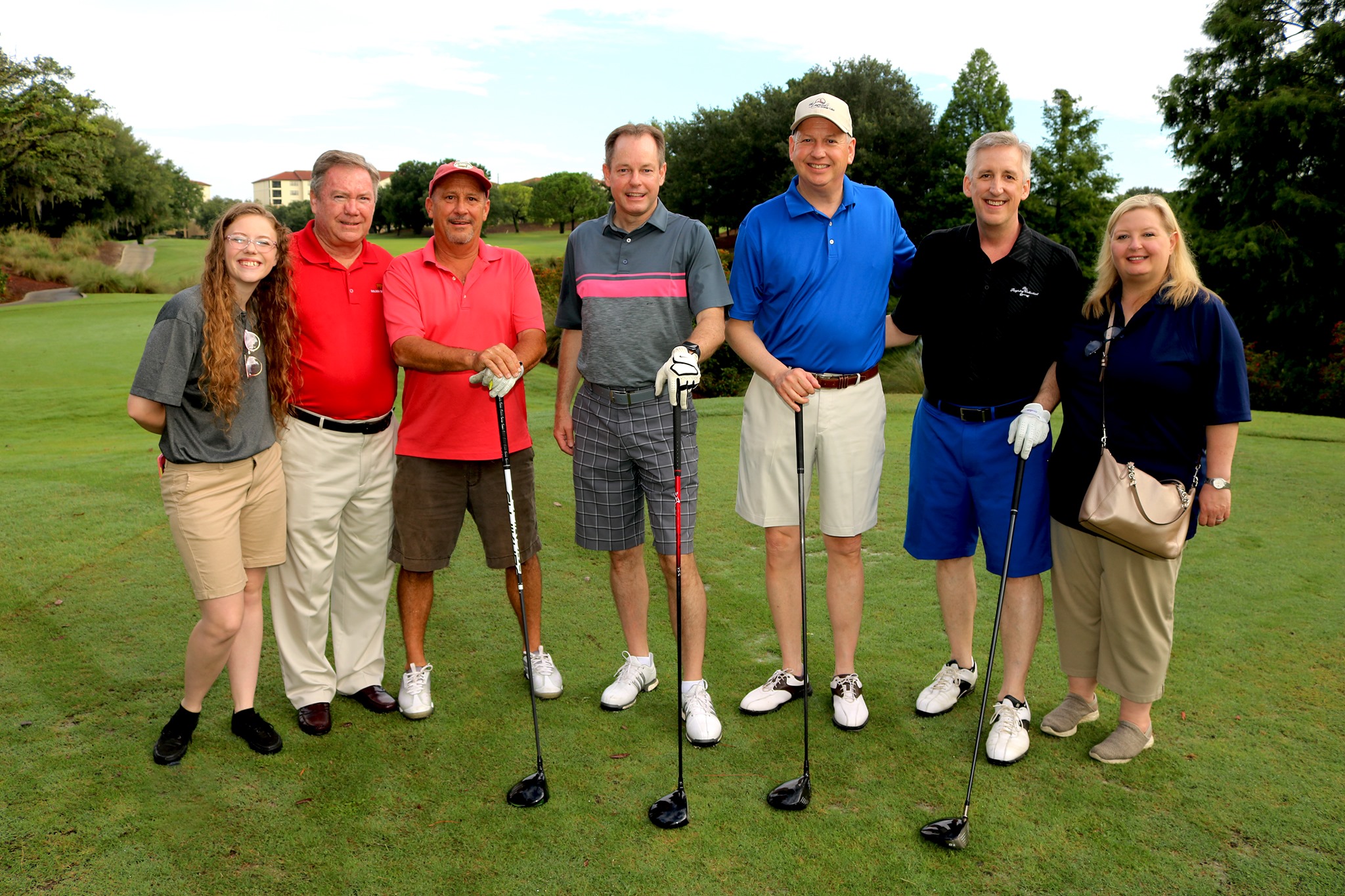 Group posing for a photo holding golf clubs.