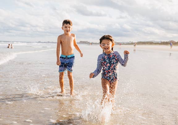 Two children running on beach near Cape Canaveral Beach Resort in Florida.