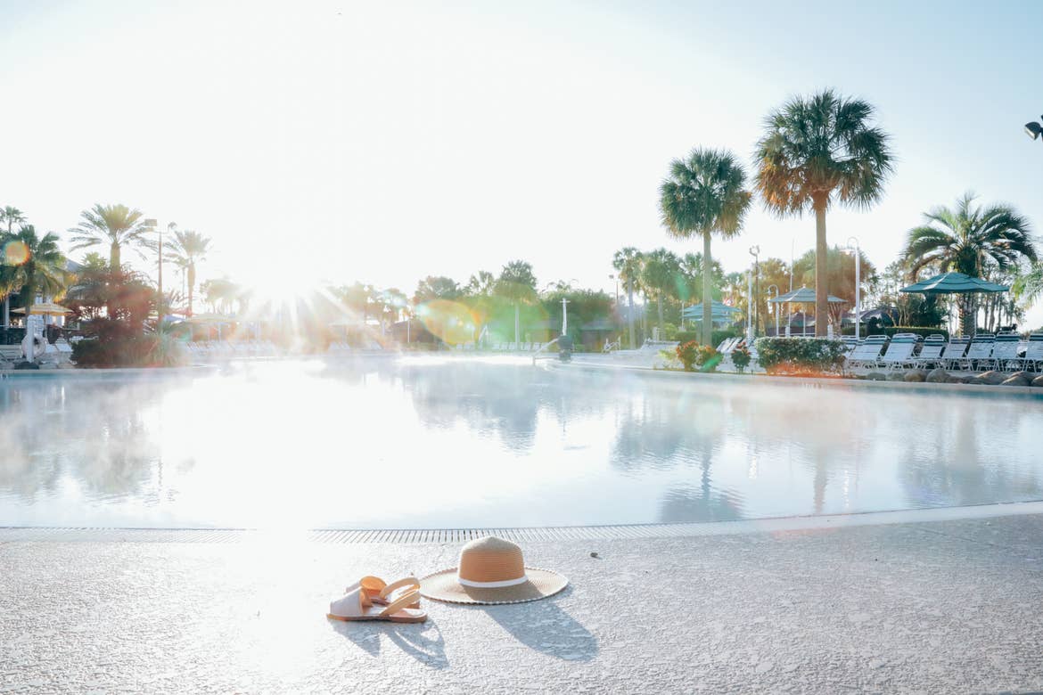 A hat and sandals lying next to the zero-entry pool in West Village at Orange Lake Resort