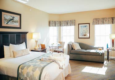 Bedroom with bed, couch, and three windows in a villa in East Village at Orange Lake Resort near Orlando, Florida