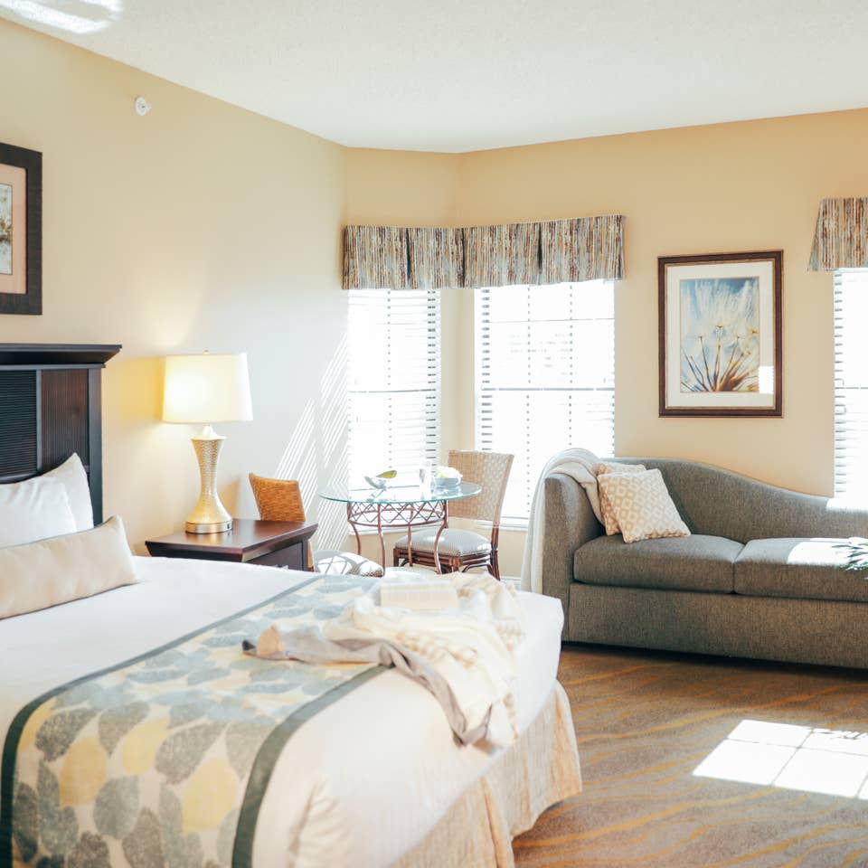 Bedroom with bed, couch, and three windows in a villa in East Village at Orange Lake Resort near Orlando, Florida