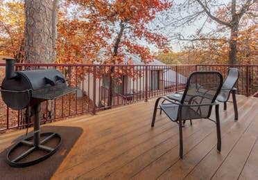 Furnished balcony with table, two chairs, and a grill in a two-bedroom cabin at Ozark Mountain Resort in Kimberling City, Missouri