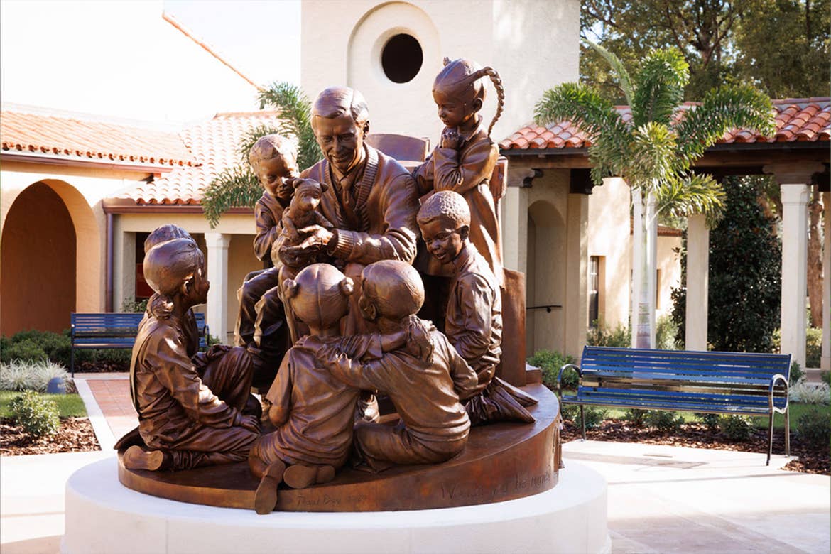 A bronze statue of Mister Fred Rogers surrounded by children.