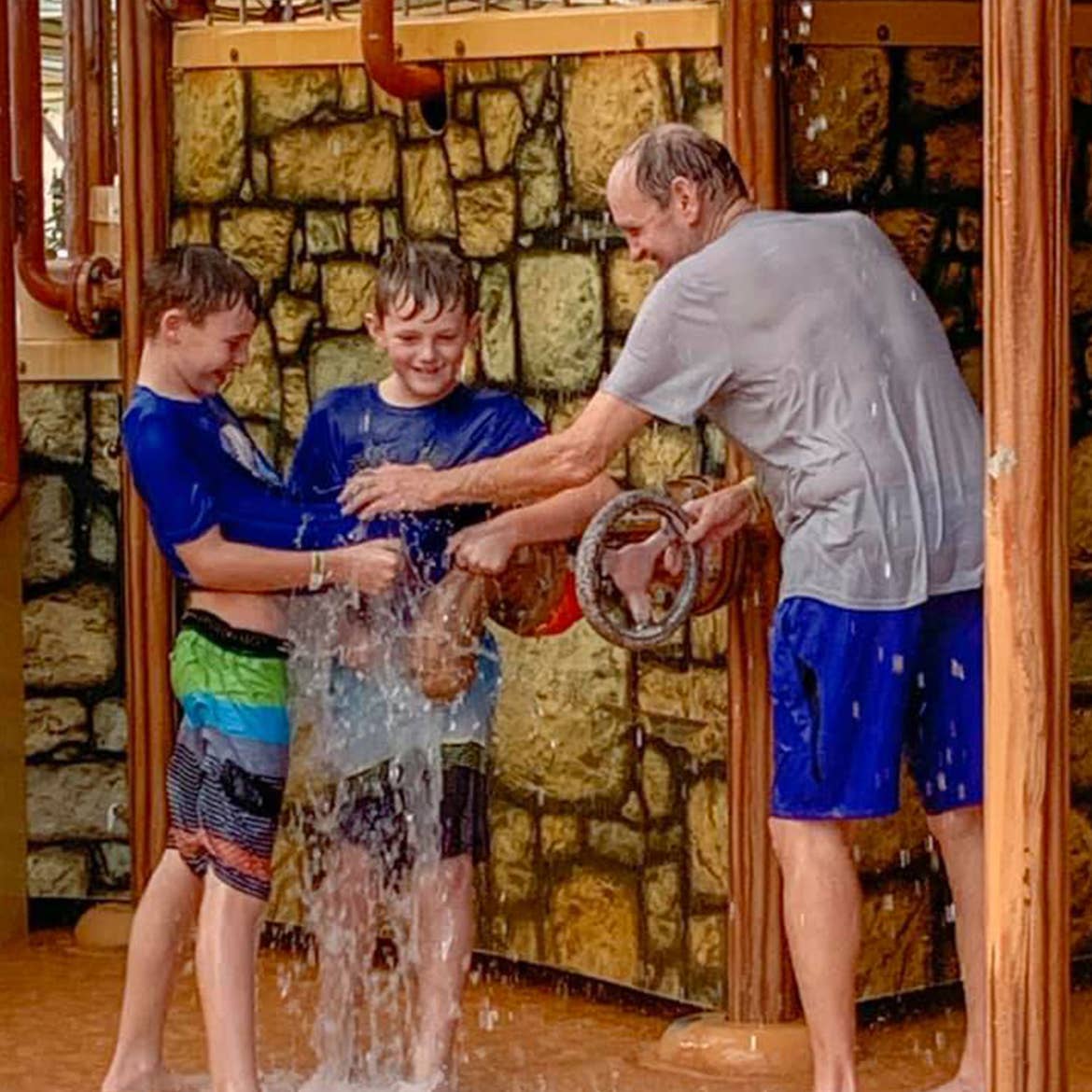 Author, Amanda Nall's father (right) and sons (left) play in the water park splash station.