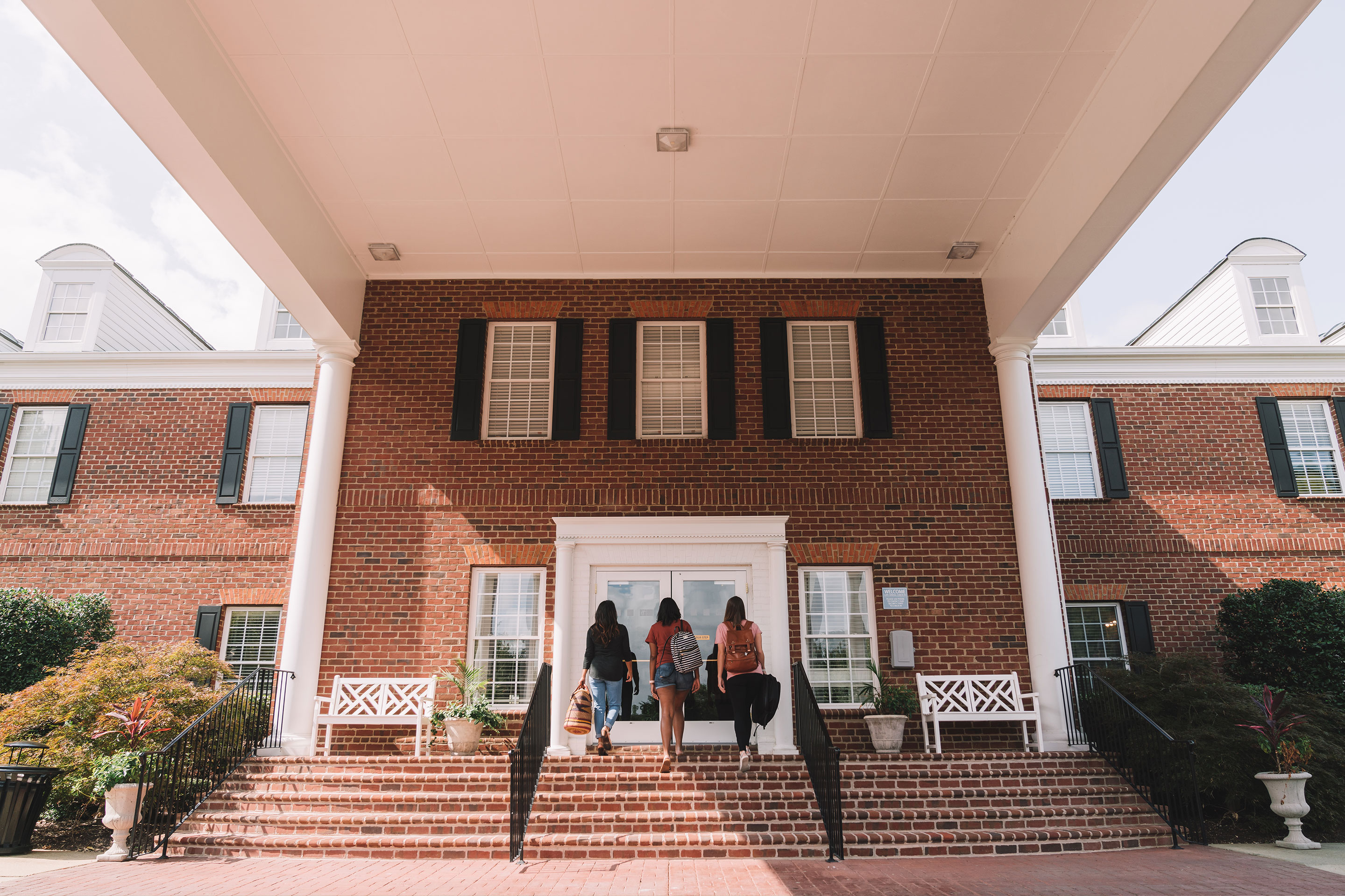 Three female guests carry their luggage into the lobby from the exterior of our Williamsburg resort in Williamsburg, Virginia.