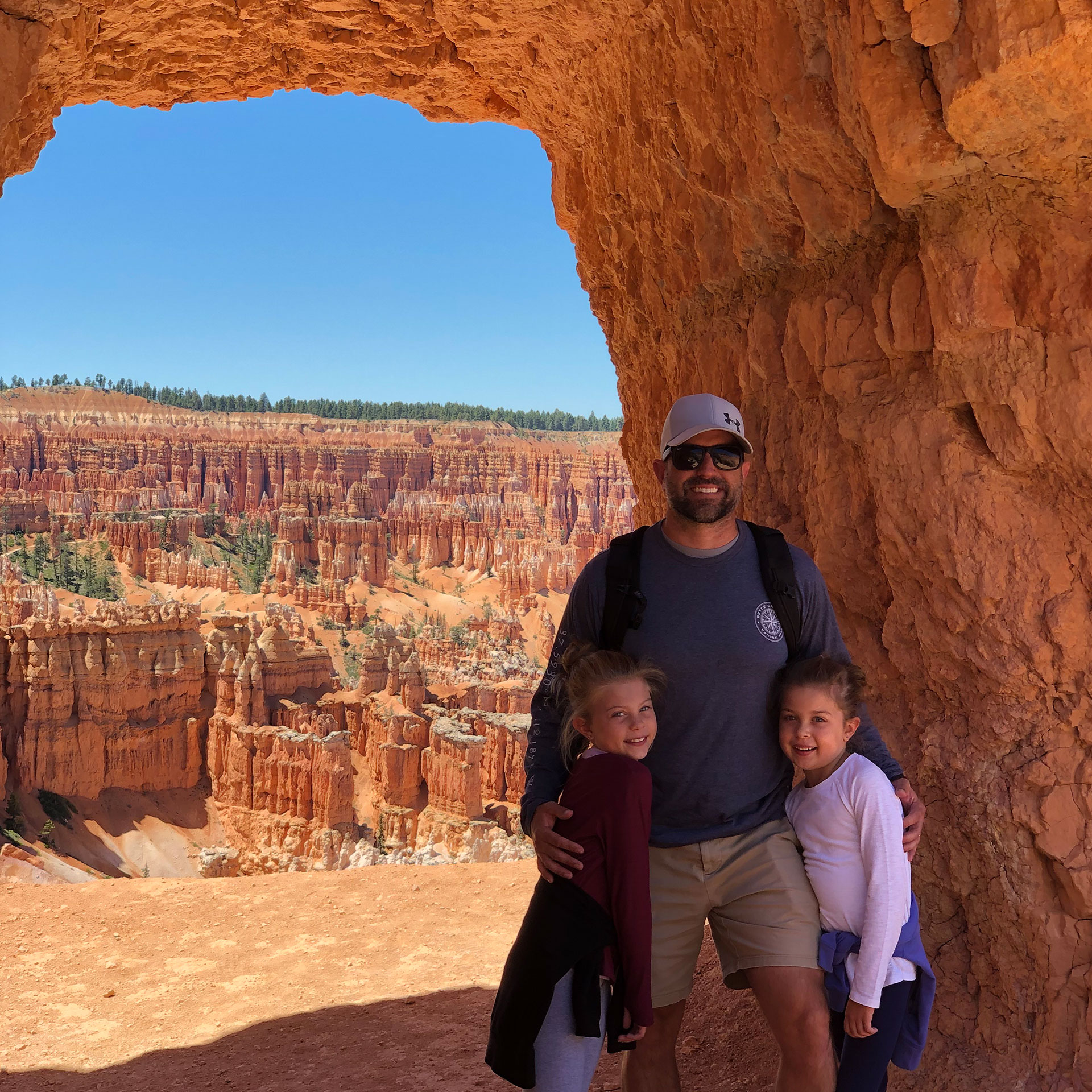Josh (middle), Kyler (right) and Kyndall (left) stand under an arch formation in front of a gorge.