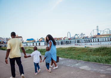 family of 4 walking along the Beach Seawall near Galveston Beach, TX