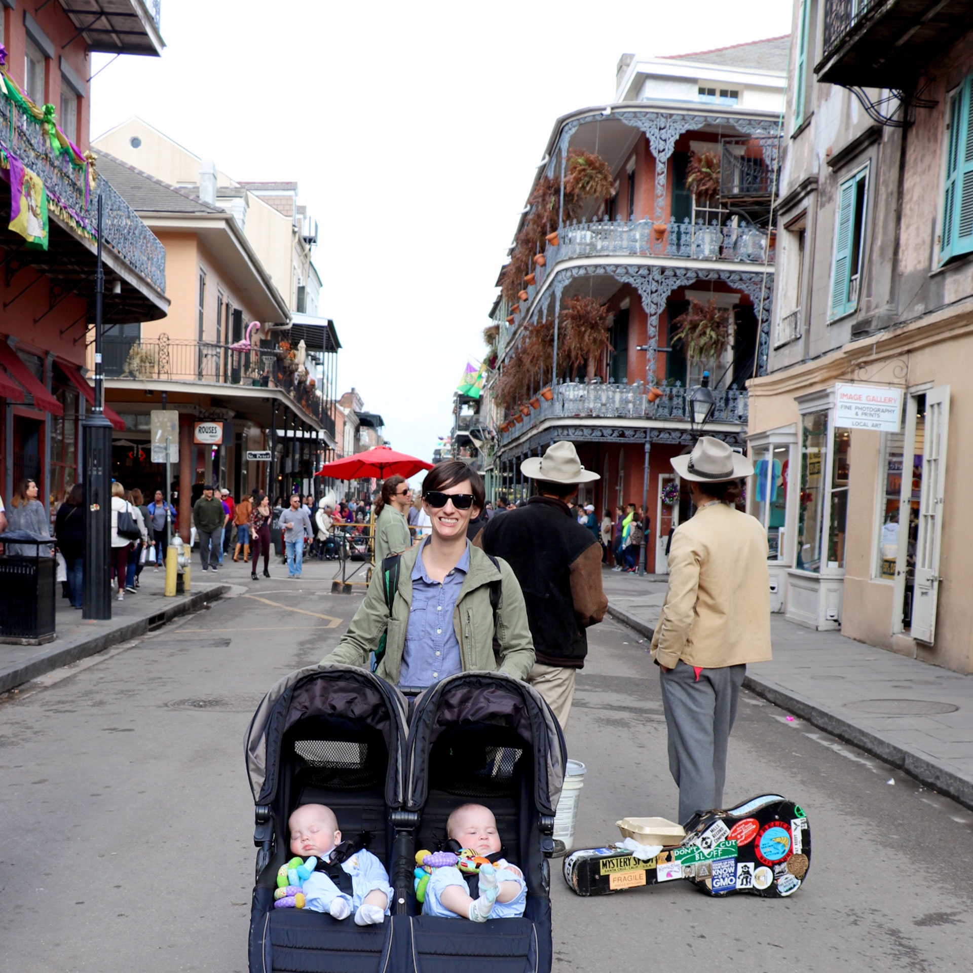 Featured Contributor, Catherine Karas's wife, stands in the middle of the French Quarter with their twin boys in a stroller.