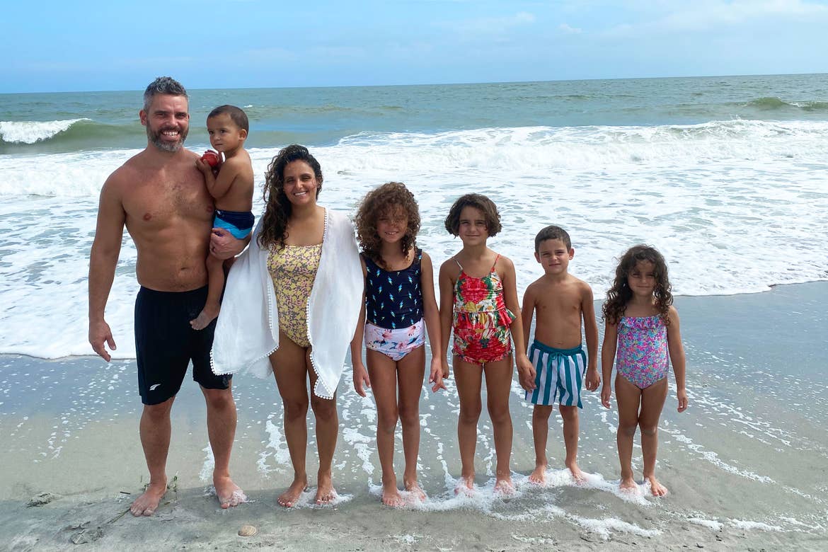 Author, Brenda Rivera Stearns (third from the left), and husband, Isaiah (far-left), stand along the sandy beach while posing with all of their children.