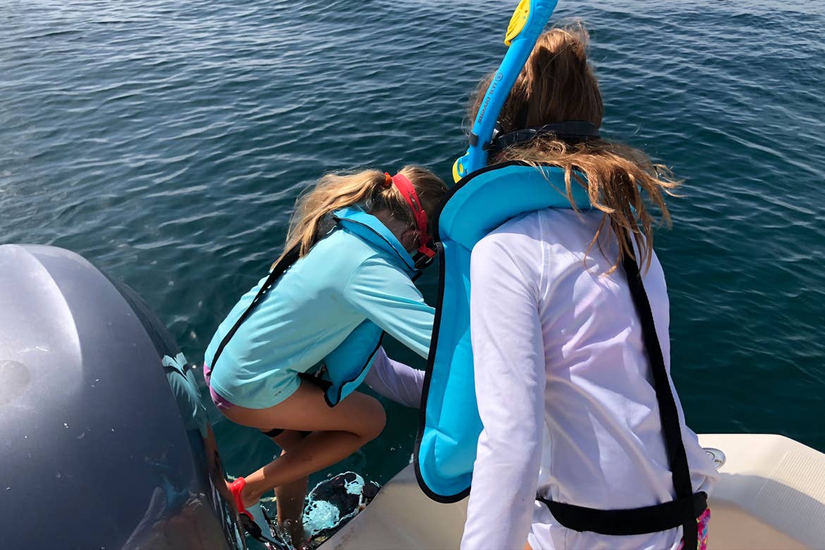 Featured Contributor, Chris Johnston's two daughters, Kyler (right) and Kyndall (left), wear multi-colored snorkel gear while stepping into the ocean.