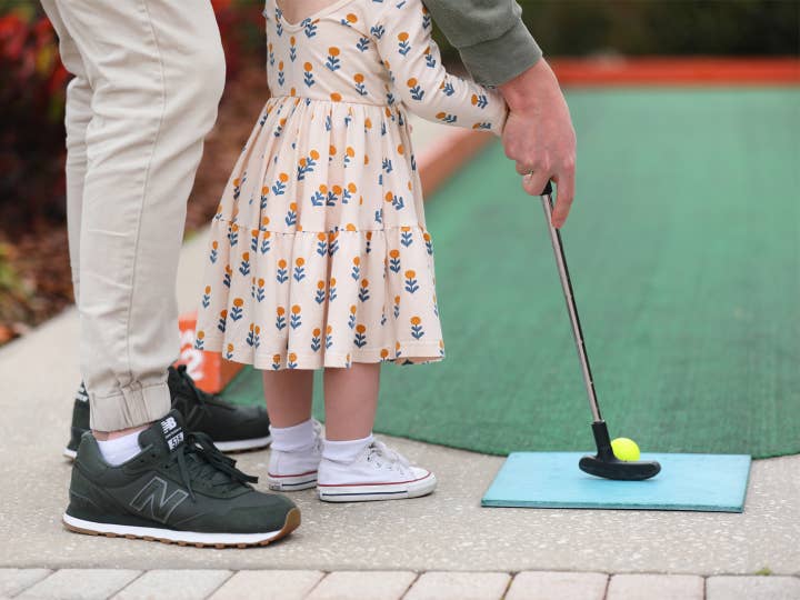 A toddler and adult playing mini golf