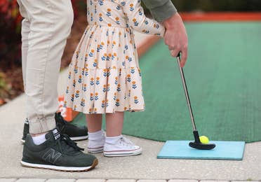 A toddler and adult playing mini golf