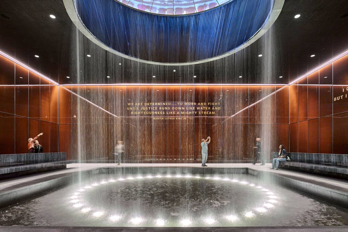 The Martin Luther King Contemplative Court has a circular water feature that drops water from the ceiling with wood-paneled walls displaying a Martin Luther King quote.