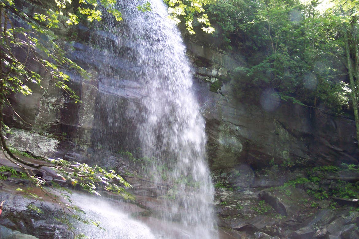 A waterfall cascades over a rock formation at Rainbow Falls Trail in Tennessee.