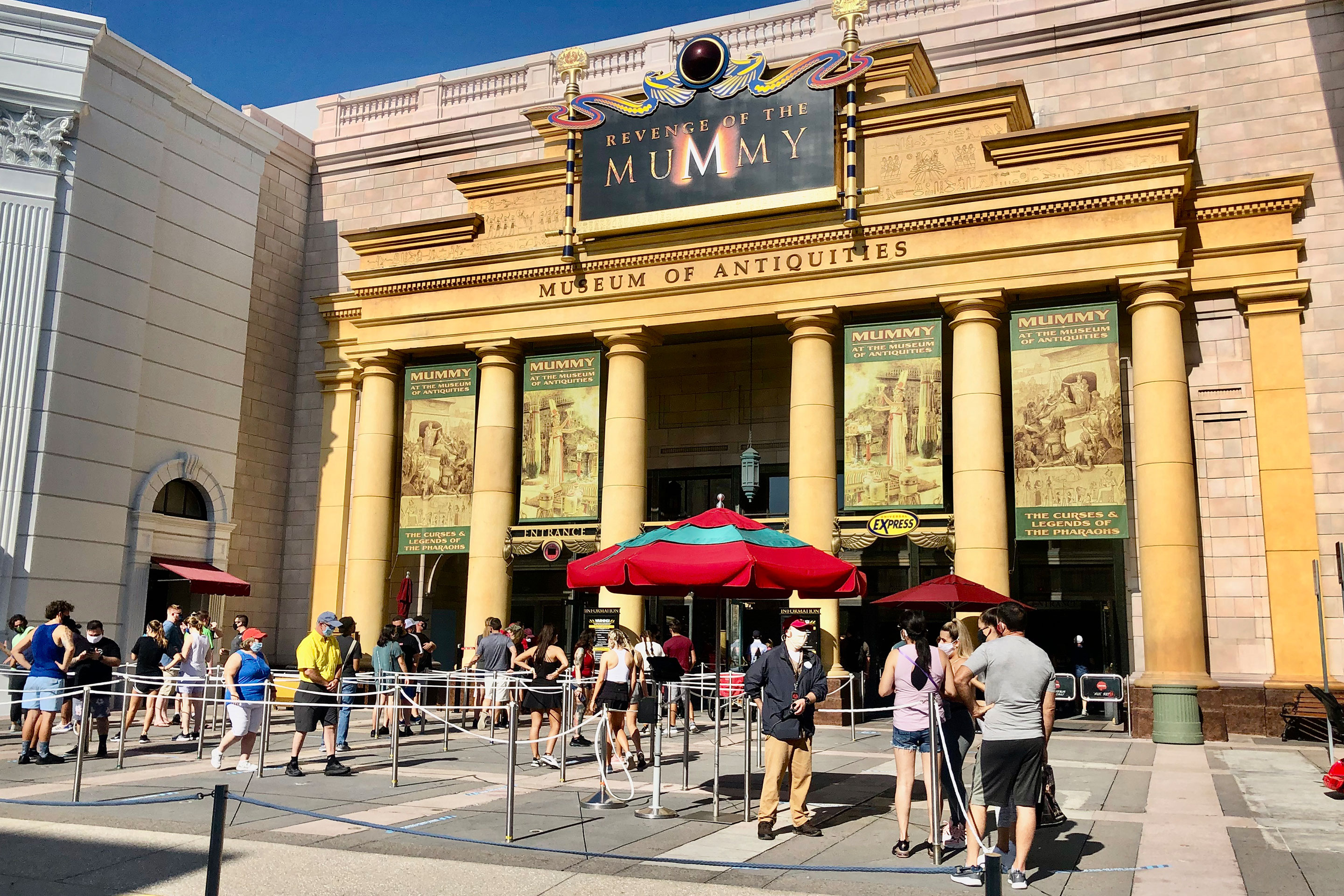 'Revenge of the Mummy' attraction entrance facade with guests in socially distant queue.