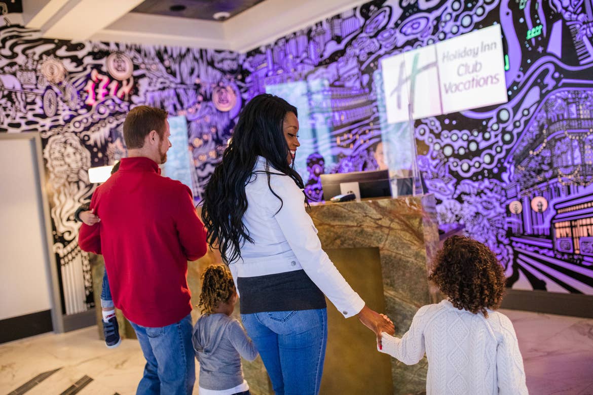Featured Contributor, Sally Butan (middle-right) of @butanclan walks towards a check-in desk near our purple animated mural in the lobby at our resort in New Orleans, Louisiana.