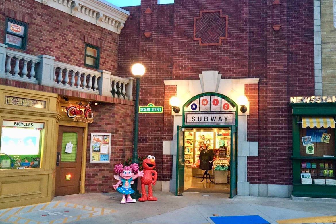Exterior shot of Sesame Street Land where Elmo and Abby Cadabby stand under the streetlamp in front of the subway.