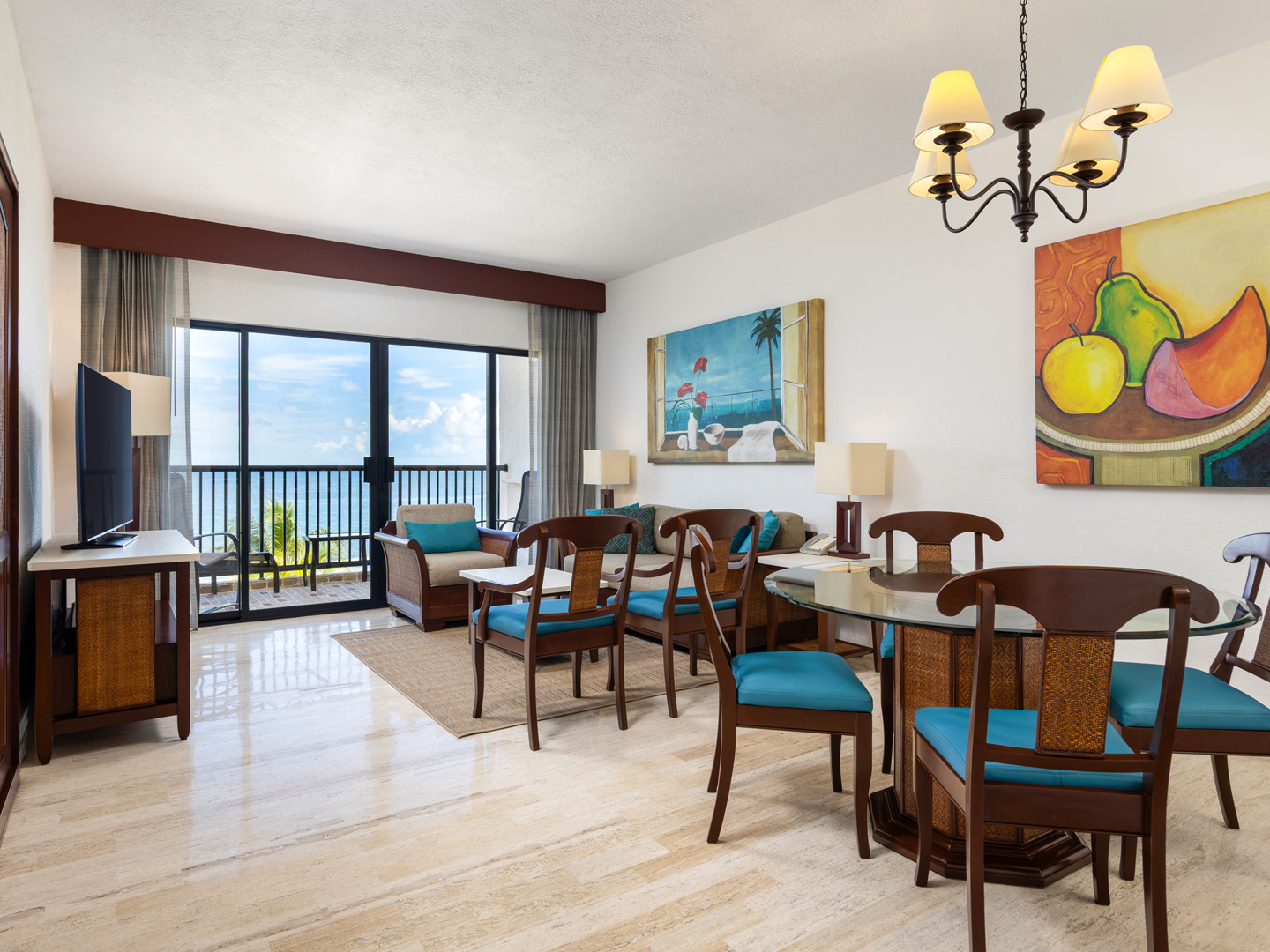 Villa living room with ocean-view balcony, sofa, and dining area.