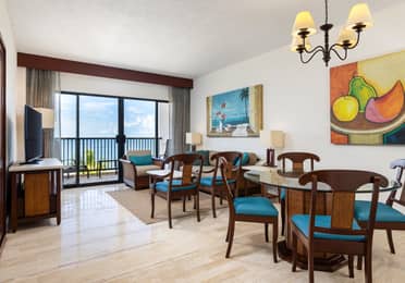 Villa living room with ocean-view balcony, sofa, and dining area.