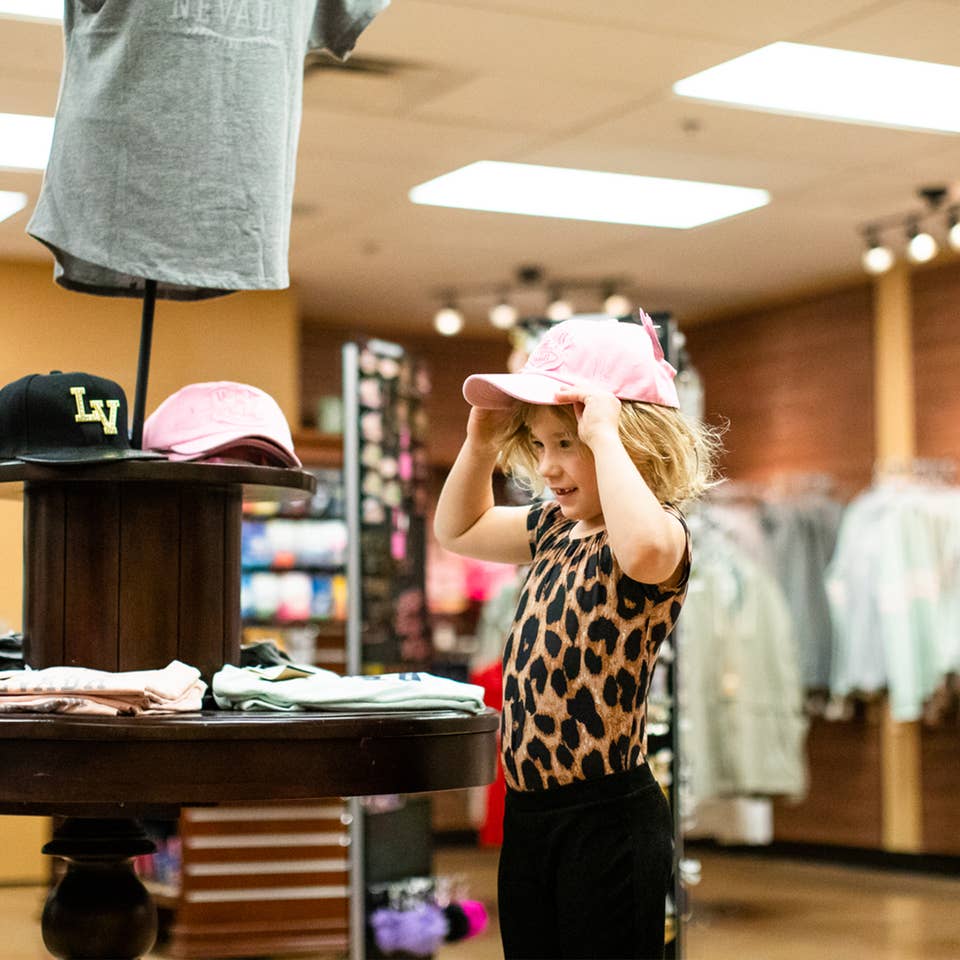 Young child trying on a Las Vegas hat in Marketplace at Desert Club Resort in Las Vegas, Nevada.