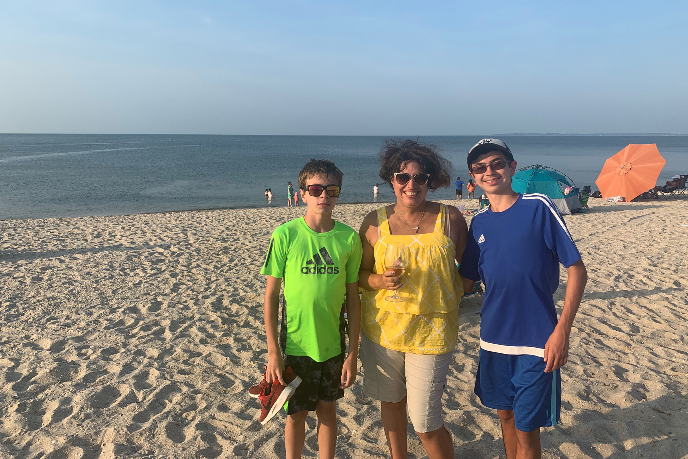 Author, Jennifer Probst (middle), and her sons (left and right) stand on the beach in front of the Cape May waterfront.