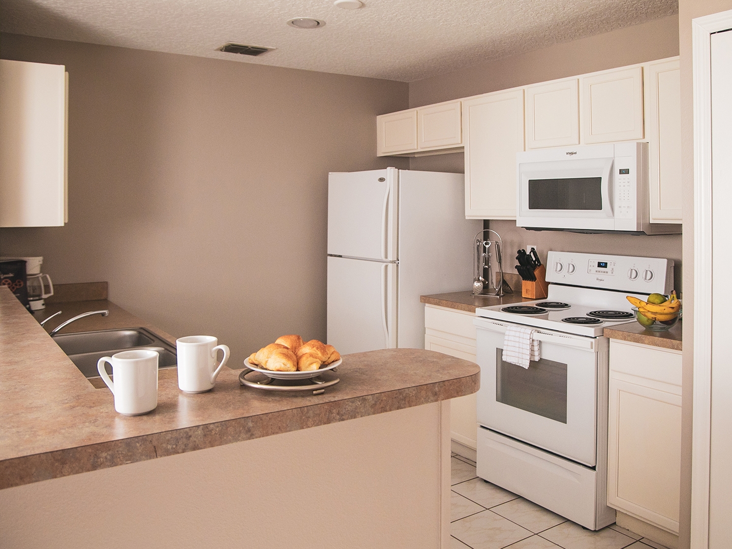 Full kitchen with fridge, stove and microwave in a two-bedroom villa at Orlando Breeze Resort in Florida.