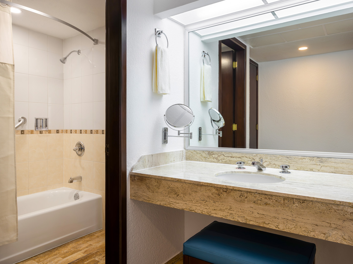 Spacious bathroom with tub, large mirror, and stone counter.
