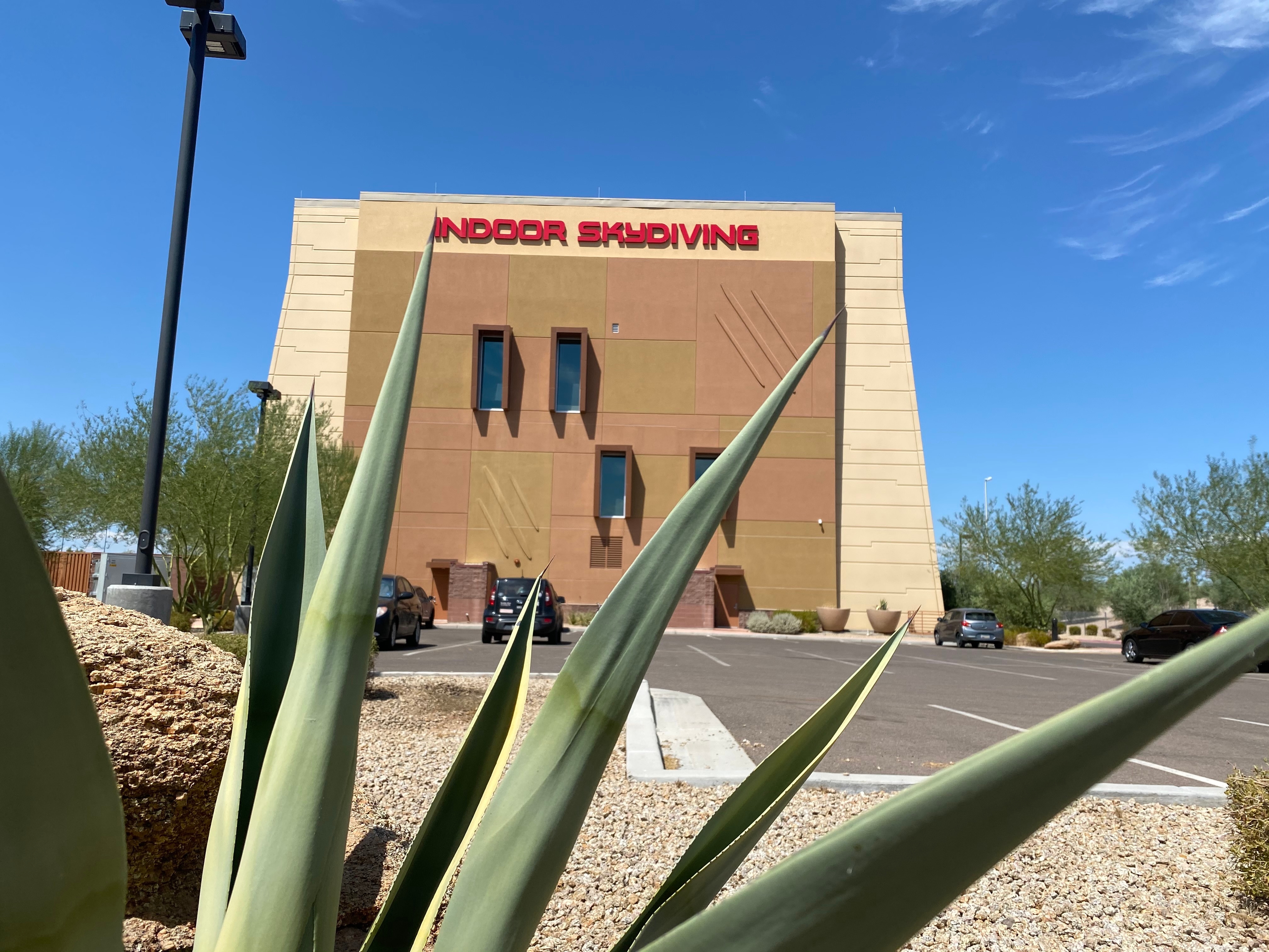 The Indoor Skydiving building with a desert plant in the foreground.
