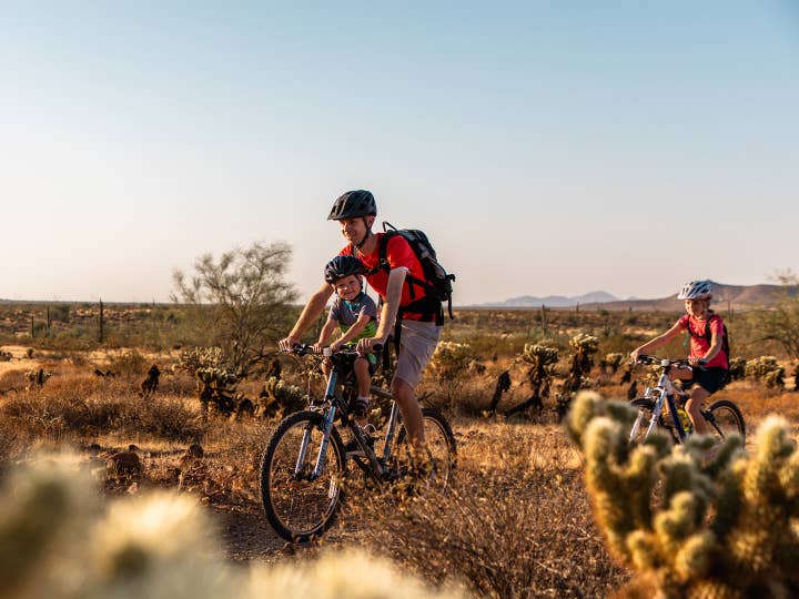 Father and two children cycling through desert near Scottsdale Resort in Arizona.