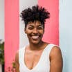 Monet Hambrick headshot in front of a pink and white striped wall.
