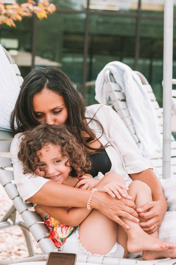 Mother kissing child on head while sitting on pool chair at Williamsburg Resort in Virginia.