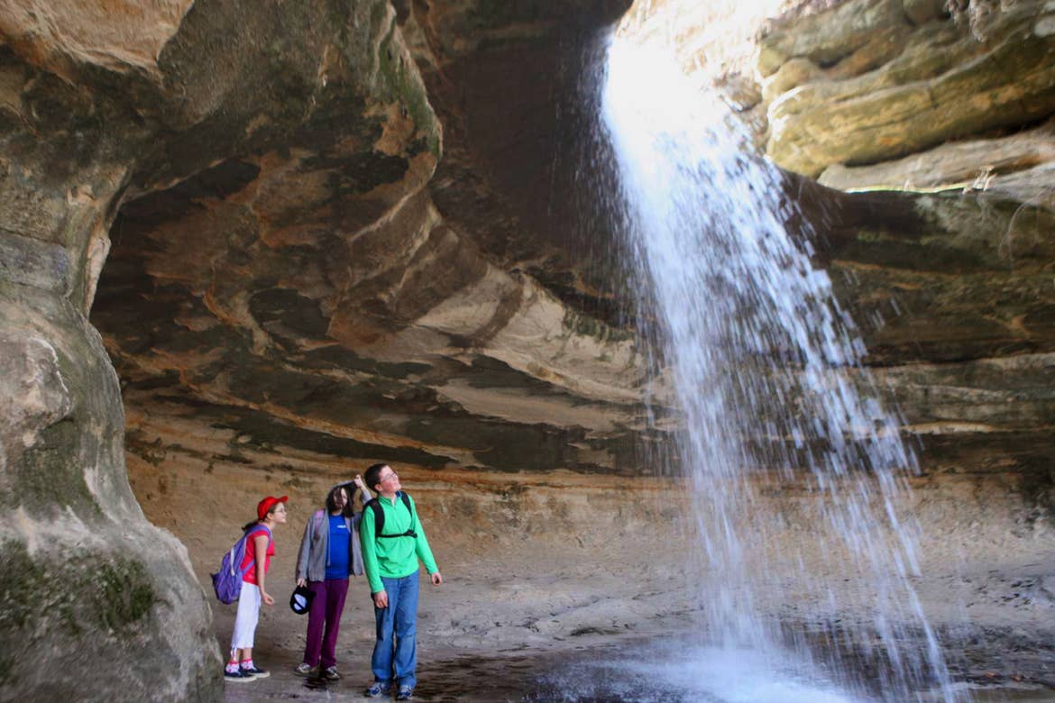 Three tweens stand under one of the LaSalle Canyon Falls at Starved Rock State Park.