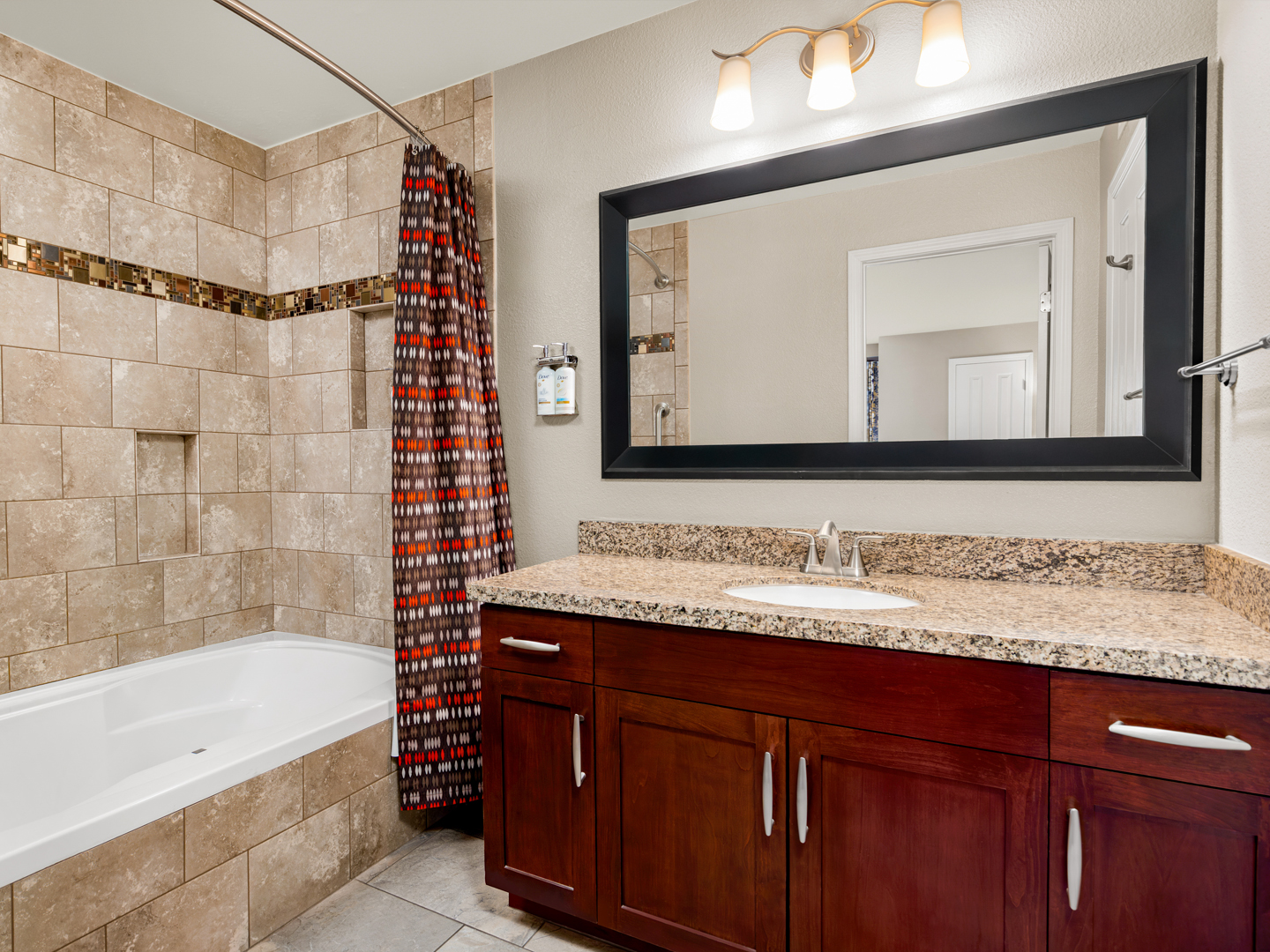 Bathroom with granite vanity and tiled shower-tub combination.
