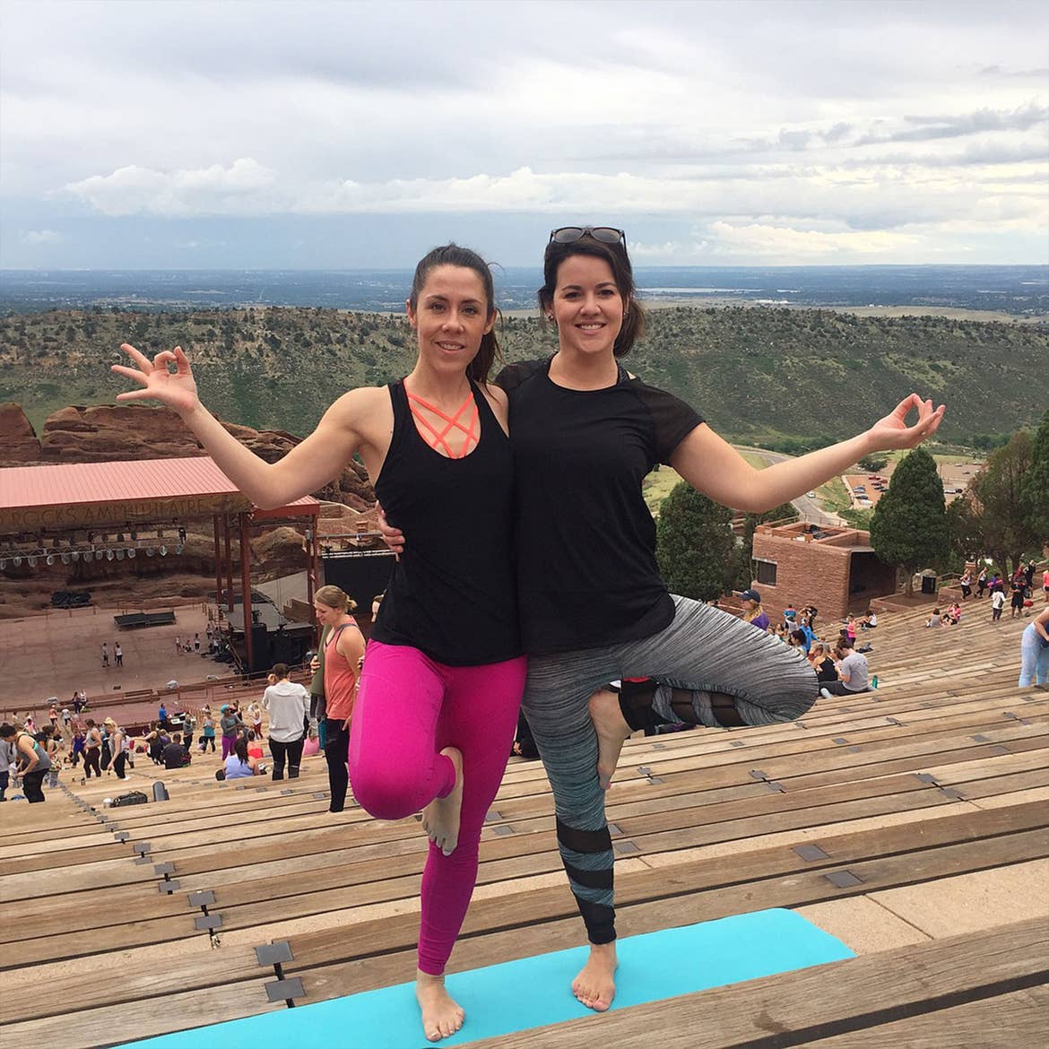 Jenn (right) completes a yoga pose with a friend outdoors at Red Rock Amphitheater.