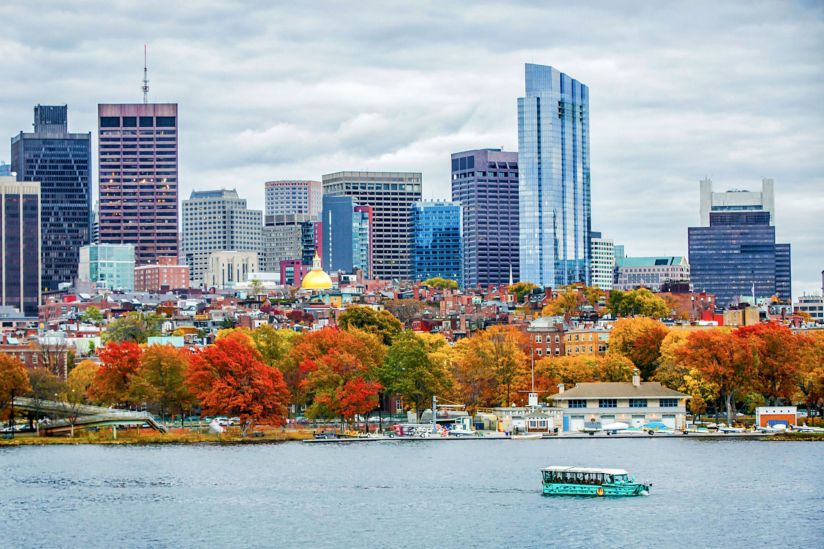 An amphibious 'Duck' vehicle floats along a river surrounded by fall foliage.
