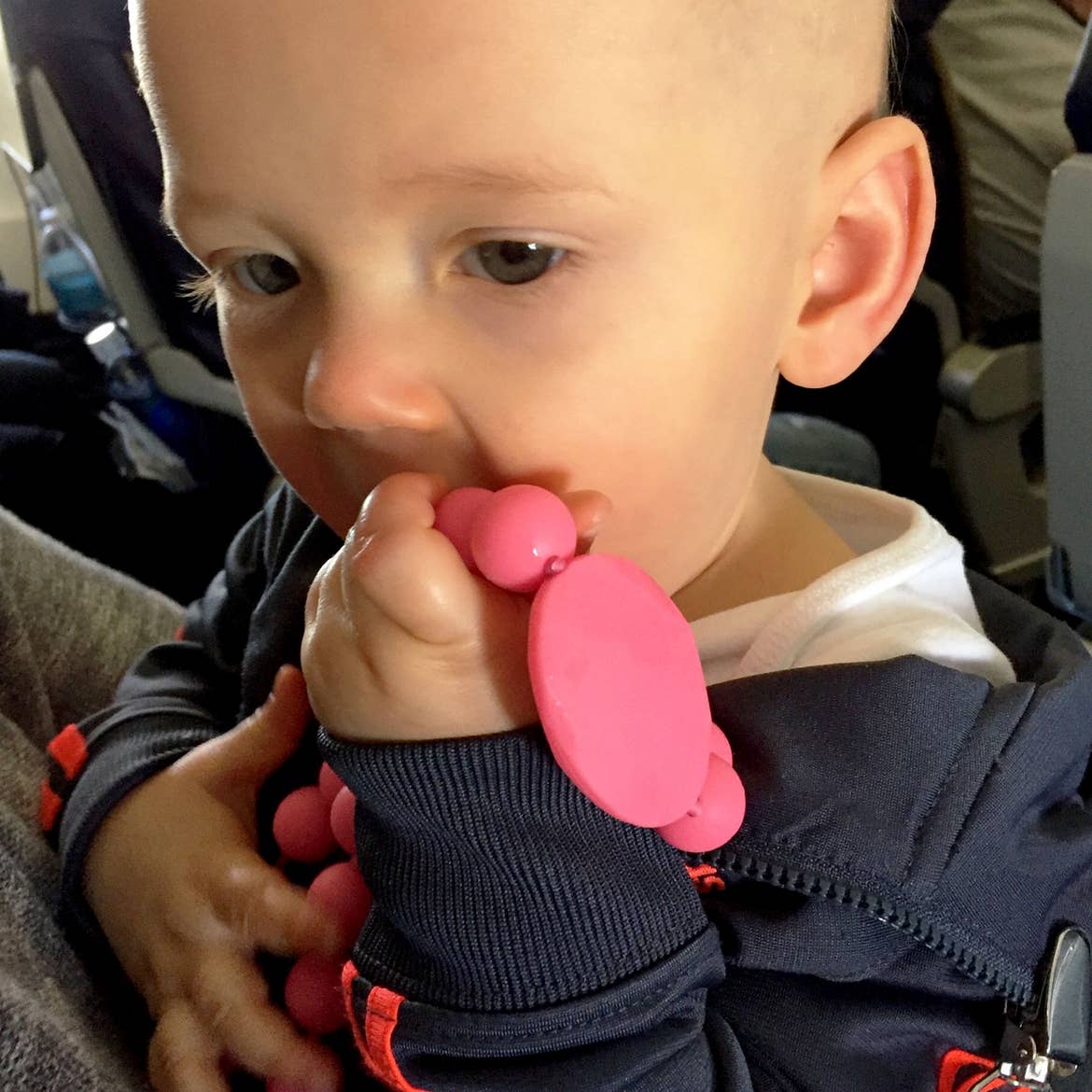Sarah's son, Logan, as an infant holds a pink teething toy in the aircraft.