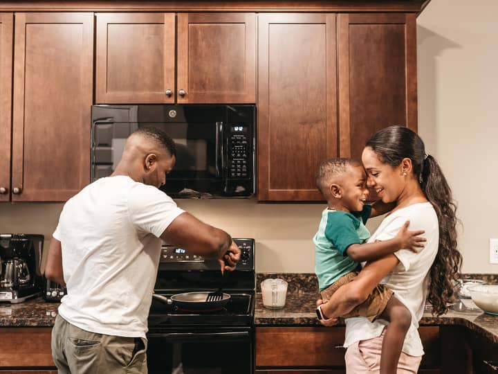 A couple and their child cooking in the a kitchen in a villa at Williamsburg Resort