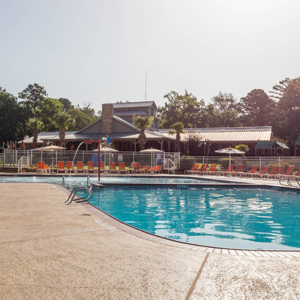 Outdoor pool with orange pool chairs surrounding it at Villages Resort in Flint, Texas.